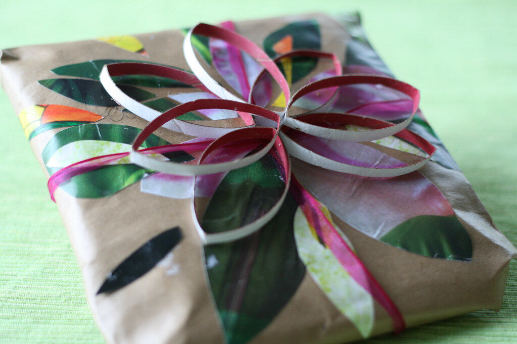 Ein Geschenk in Packpapier mit einer Schleife aus bunten Papierstreifen